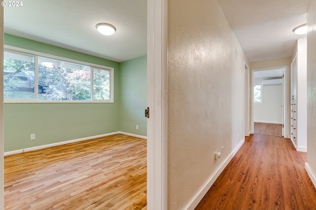 corridor featuring a wall mounted AC, baseboards, and wood finished floors