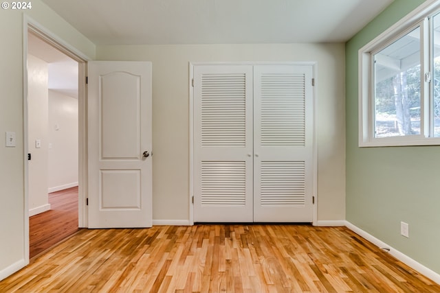 unfurnished bedroom featuring a closet, light wood-type flooring, and baseboards