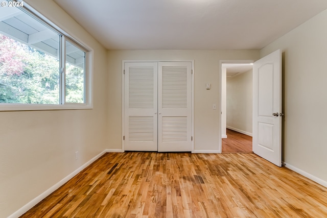 unfurnished bedroom with a closet, light wood-style flooring, and baseboards