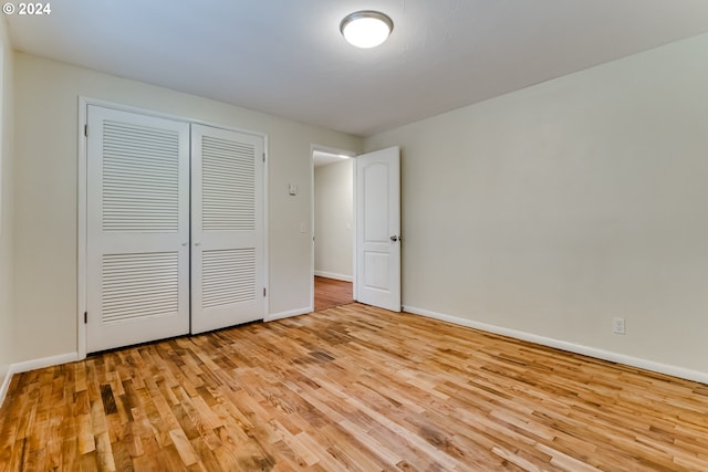 unfurnished bedroom featuring a closet, baseboards, and wood finished floors