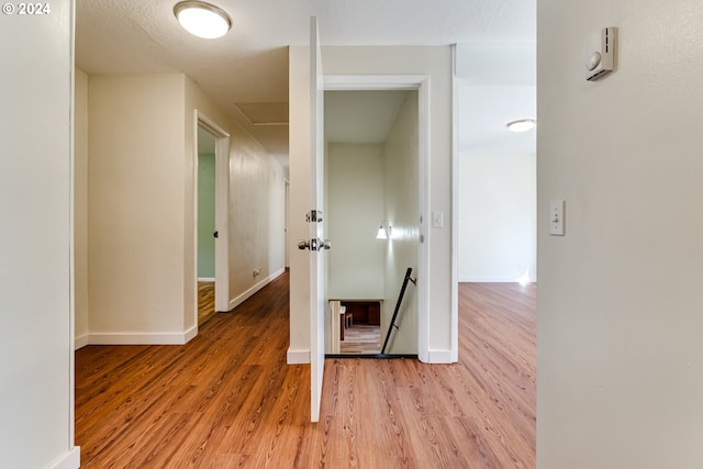 corridor featuring an upstairs landing, attic access, light wood-style flooring, and baseboards