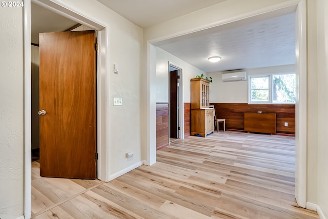 hall with wainscoting, wooden walls, wood finished floors, a wall mounted air conditioner, and baseboards