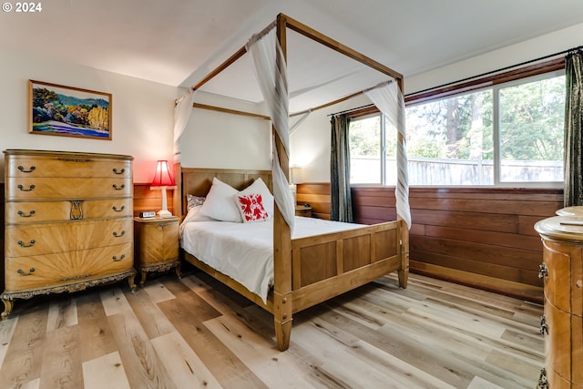 bedroom with wood walls and light wood-style flooring