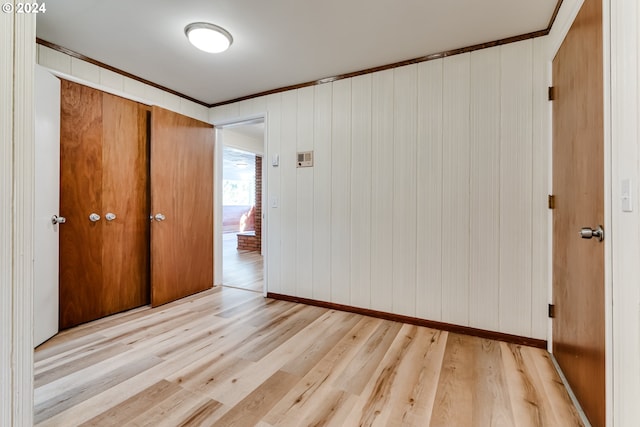 unfurnished bedroom featuring ornamental molding, a closet, light wood-style flooring, and baseboards