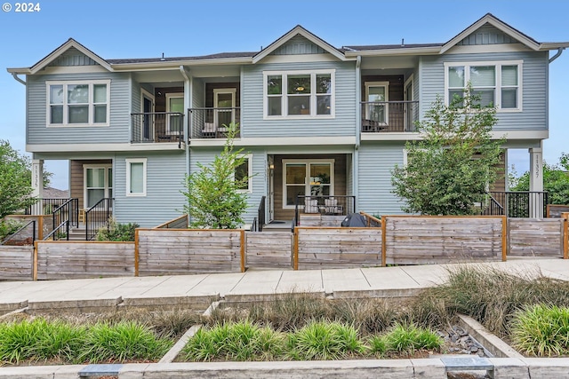 view of property featuring a balcony and a fenced front yard