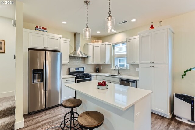 kitchen featuring sink, appliances with stainless steel finishes, light hardwood / wood-style flooring, wall chimney exhaust hood, and decorative backsplash