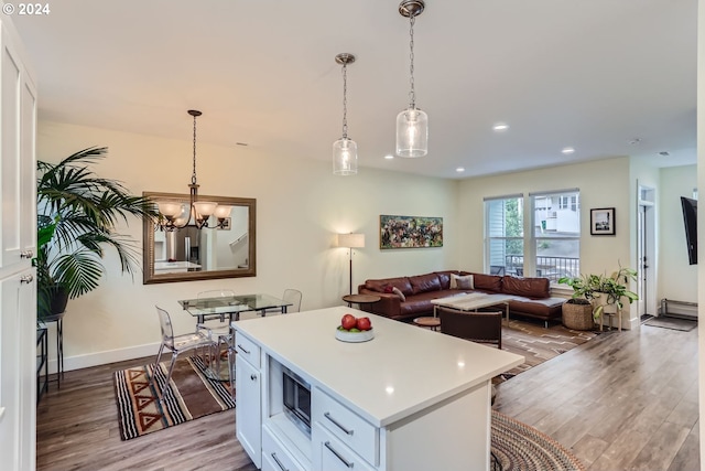 kitchen with decorative light fixtures, light hardwood / wood-style floors, white cabinetry, and a center island