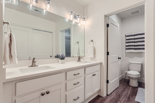 bathroom with dual vanity, hardwood / wood-style floors, and toilet