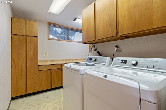 clothes washing area featuring washer and clothes dryer and cabinets