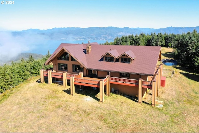 rear view of house featuring a yard and a deck with mountain view