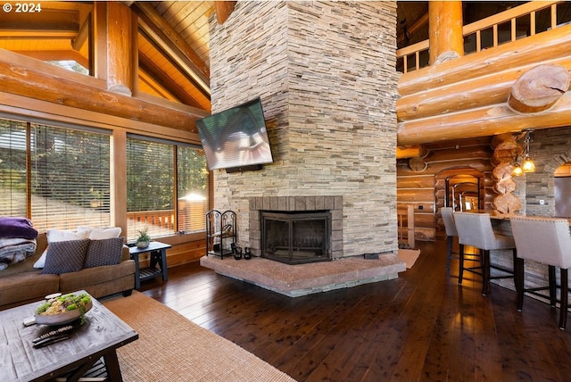 living room featuring a stone fireplace, log walls, dark wood-type flooring, and high vaulted ceiling