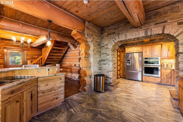 kitchen featuring rustic walls, hanging light fixtures, stone countertops, a notable chandelier, and appliances with stainless steel finishes