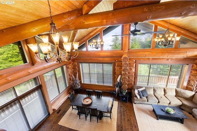 living room with a notable chandelier, rustic walls, dark hardwood / wood-style flooring, a wealth of natural light, and lofted ceiling with beams