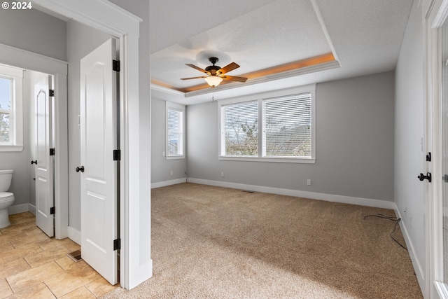 carpeted spare room featuring a textured ceiling, a tray ceiling, and ceiling fan