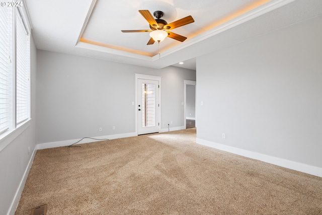 unfurnished room with ceiling fan, a raised ceiling, and carpet floors