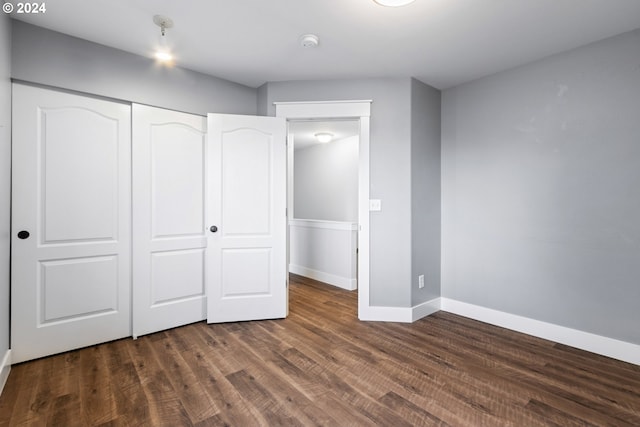 unfurnished bedroom with a closet and dark wood-type flooring