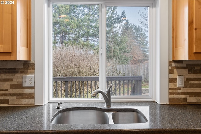 room details featuring decorative backsplash, dark stone counters, and sink