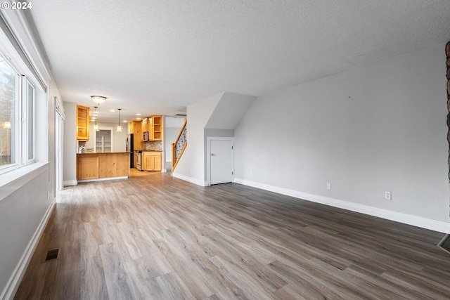 unfurnished living room featuring wood-type flooring and a textured ceiling