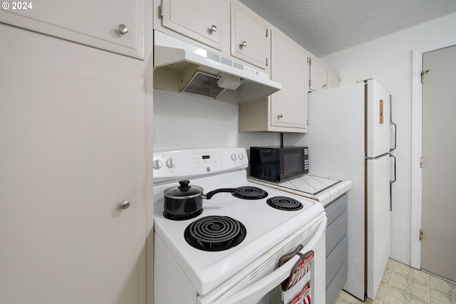 kitchen with a textured ceiling, white appliances, white cabinetry, and tile countertops