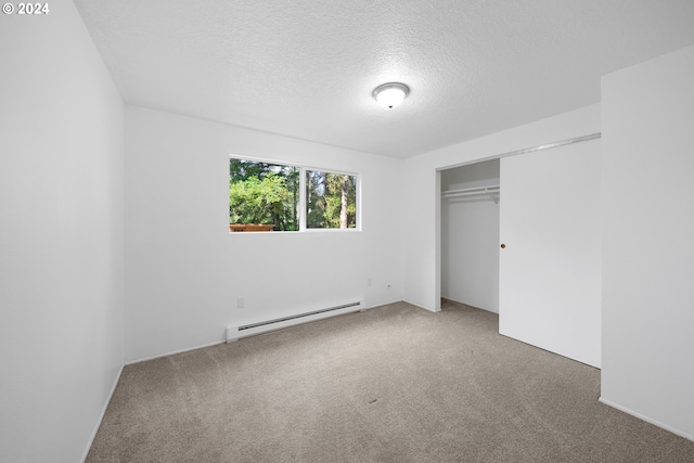 unfurnished bedroom featuring carpet floors, a textured ceiling, baseboard heating, and a closet