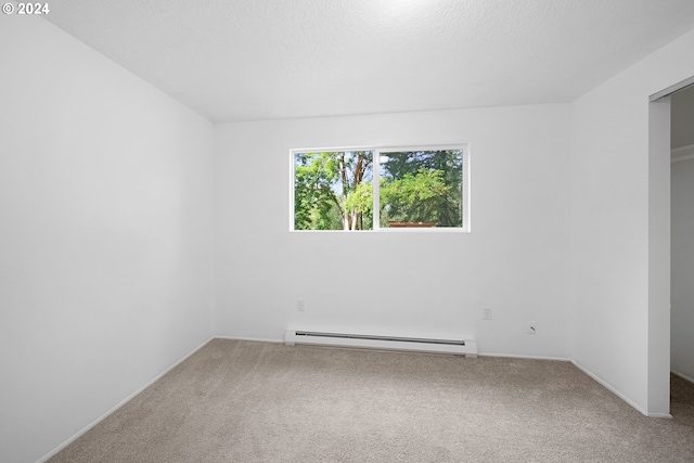 empty room featuring a baseboard heating unit, carpet, and a textured ceiling