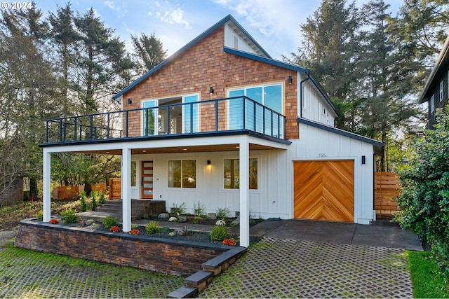 back of property featuring covered porch, a garage, and a balcony