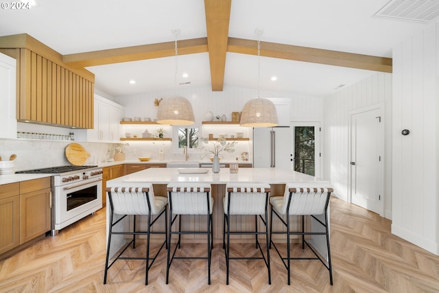 kitchen featuring high end appliances, light parquet floors, a kitchen island with sink, and a breakfast bar area