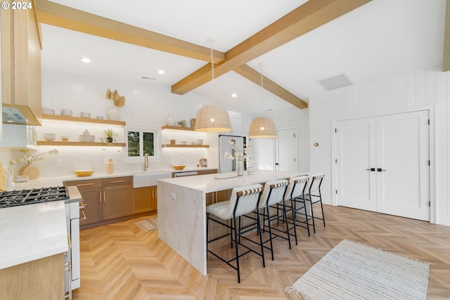 kitchen featuring beam ceiling, sink, hanging light fixtures, a kitchen island with sink, and a kitchen breakfast bar