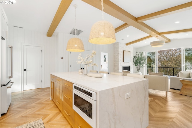 kitchen with decorative light fixtures, light parquet flooring, a center island, white appliances, and light stone counters