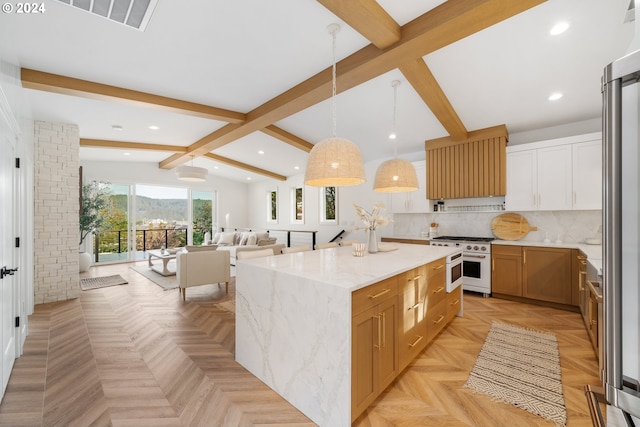 kitchen with backsplash, a spacious island, high end stove, hanging light fixtures, and light stone counters