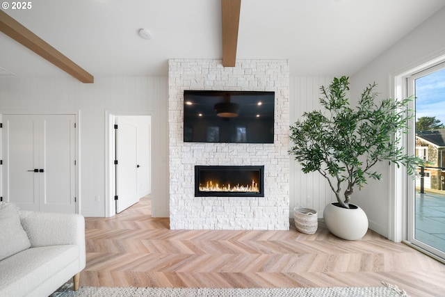 living room with beam ceiling, light parquet flooring, wooden walls, and a stone fireplace