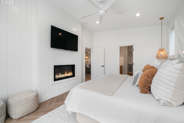 bedroom with ceiling fan, light parquet flooring, and wooden walls