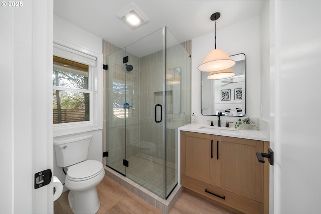 bathroom with vanity, toilet, hardwood / wood-style floors, and a shower with door