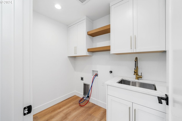 laundry area with sink, light wood-type flooring, washer hookup, electric dryer hookup, and cabinets