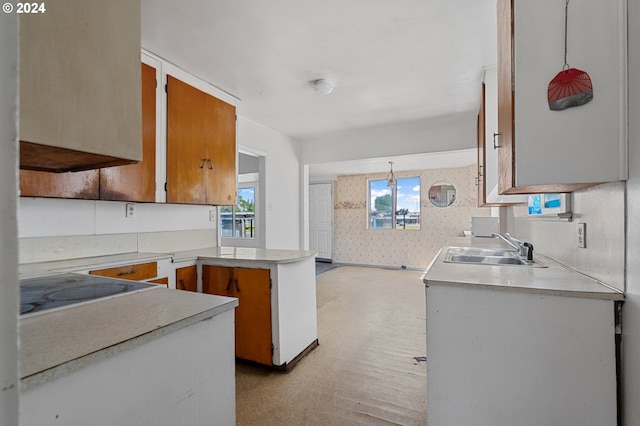 kitchen featuring pendant lighting, stovetop, kitchen peninsula, and sink