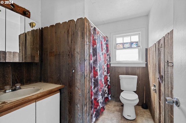 bathroom featuring vanity, wood walls, and toilet