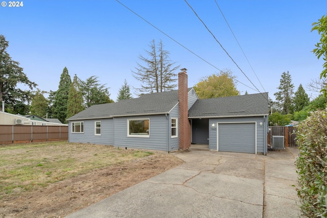 back of house featuring a yard, central AC, and a garage