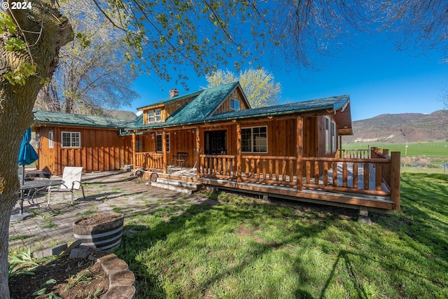 back of house with a lawn, a patio area, and a deck with mountain view