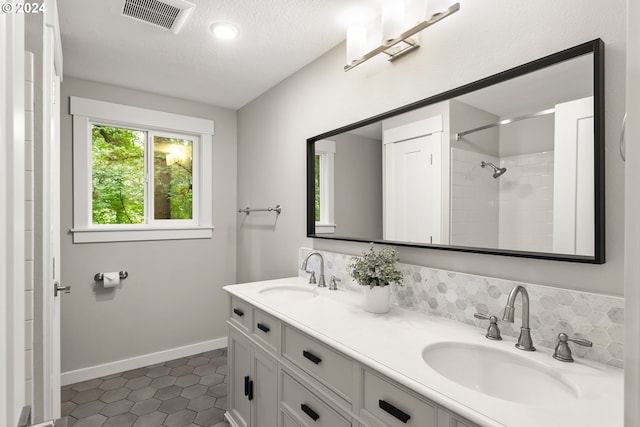 bathroom featuring a textured ceiling, vanity, a shower, and tile patterned floors