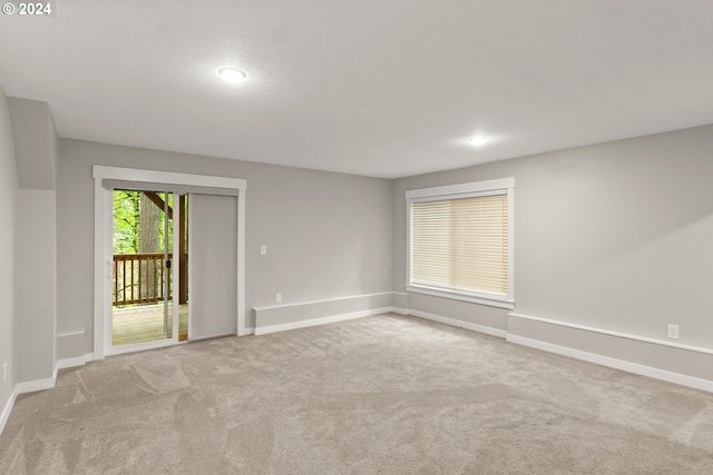 carpeted spare room featuring a textured ceiling and a healthy amount of sunlight