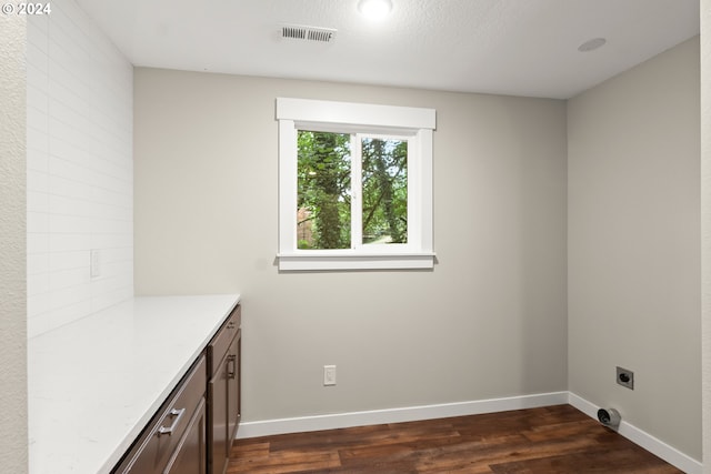 clothes washing area with dark hardwood / wood-style floors, a textured ceiling, cabinets, and electric dryer hookup