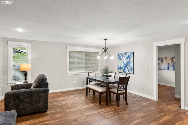 dining area featuring a textured ceiling, a notable chandelier, and dark hardwood / wood-style flooring