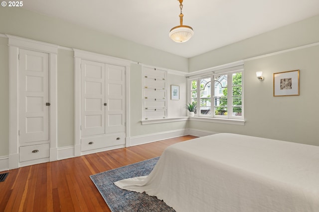 bedroom with wood-type flooring, baseboards, and a closet