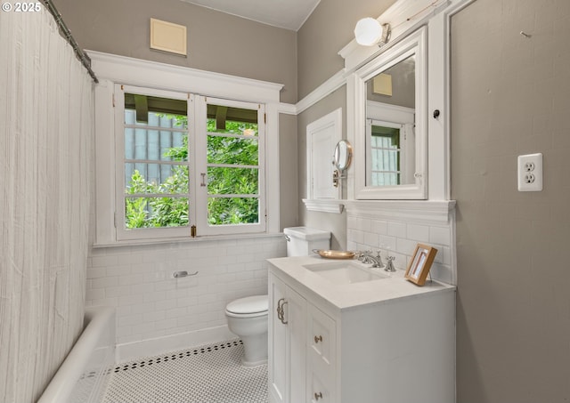 bathroom with toilet, tile walls, tile patterned flooring, vanity, and shower / bathtub combination with curtain