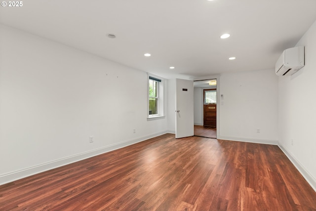 spare room with an AC wall unit, recessed lighting, dark wood finished floors, and baseboards