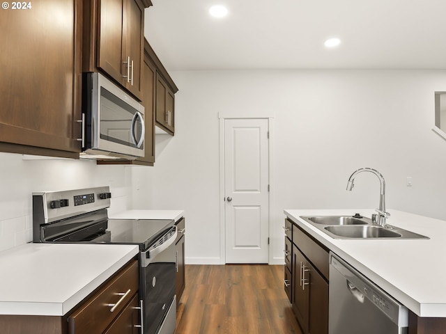 kitchen with a kitchen island with sink, sink, dark hardwood / wood-style floors, dark brown cabinets, and stainless steel appliances