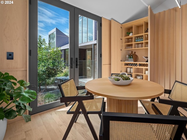 dining room with french doors, light hardwood / wood-style flooring, and vaulted ceiling