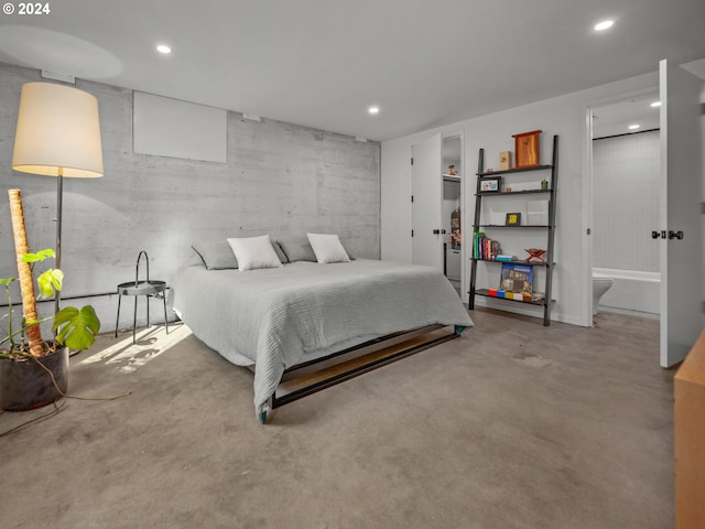 bedroom with ensuite bathroom and concrete floors