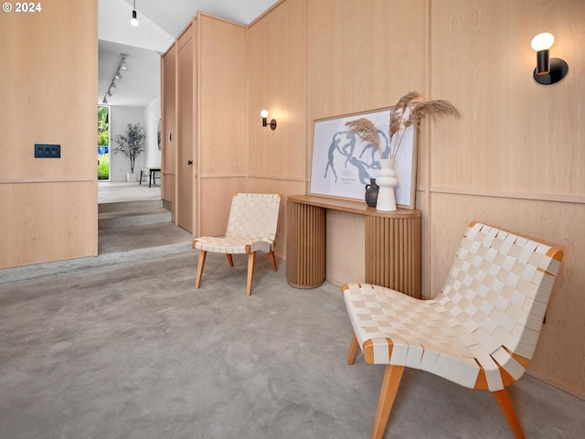 sitting room with wooden walls and vaulted ceiling