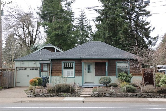 view of front facade featuring driveway, roof with shingles, and an attached garage